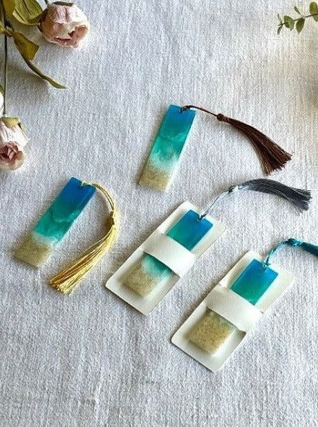 Image of ocean-inspired resin bookmarks featuring intricate designs reminiscent of waves, and sand, perfect for book lovers seeking coastal charm in their reading experience.