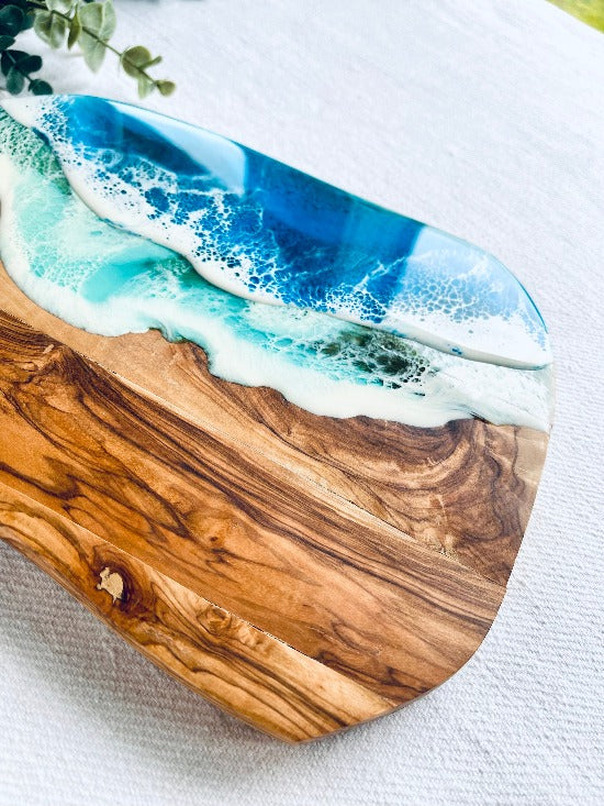 Olive charcuterie board with handle featuring captivating ocean wave resin art - a harmonious blead of nature and epoxy art.