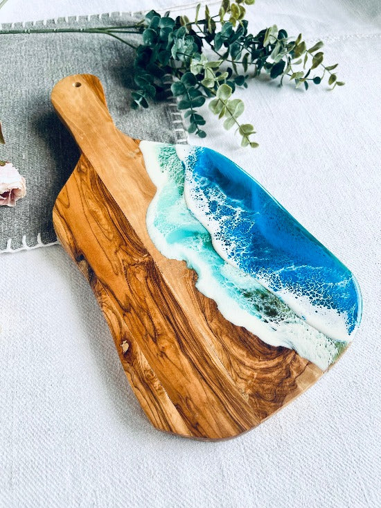 Olive charcuterie board with handle featuring captivating ocean wave resin art - a harmonious blead of nature and epoxy art.