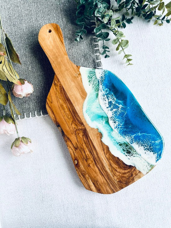 Olive charcuterie board with handle featuring captivating ocean wave resin art - a harmonious blead of nature and epoxy art.