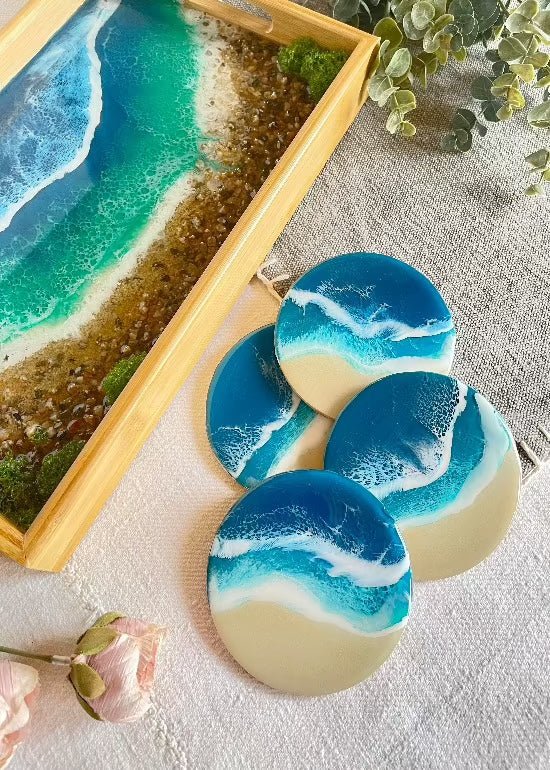 Resin art serving tray featuring a bamboo base, adorned with sea shells and sand, encapsulated in ocean wave designs created with resin. Includes a round set of 4 coasters with waves.