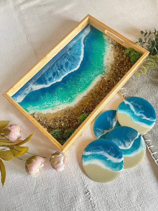 Resin art serving tray featuring a bamboo base, adorned with sea shells and sand, encapsulated in ocean wave designs created with resin. Includes a round set of 4 coasters with waves.