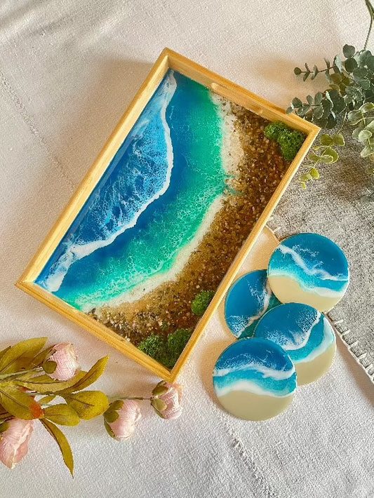 Resin art serving tray featuring a bamboo base, adorned with sea shells and sand, encapsulated in ocean wave designs created with resin. Includes a round set of 4 coasters with waves.