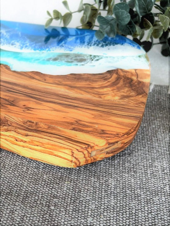 Olive charcuterie board with handle featuring captivating ocean wave resin art - a harmonious blead of nature and epoxy art.