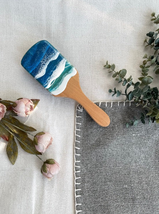 Handcrafted hairbrush featuring resin art with swirling ocean waves design.