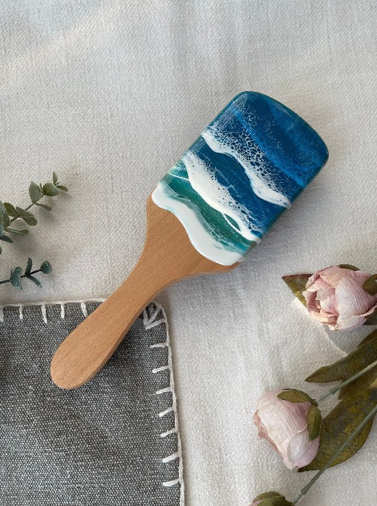 Handcrafted hairbrush featuring resin art with swirling ocean waves design.