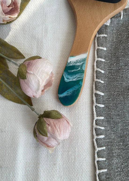 Handcrafted hairbrush featuring resin art with swirling ocean waves design.