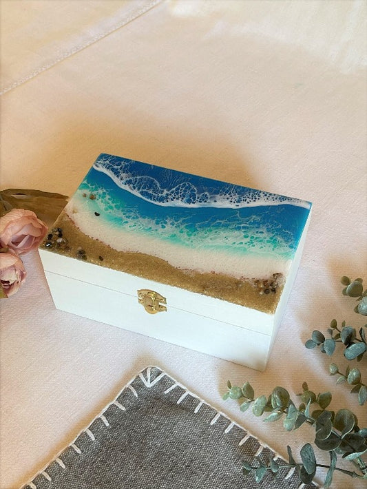 Hand-painted wooden box adorned with resin art depicting ocean waves, seashells, and sand, a unique and artistic product.