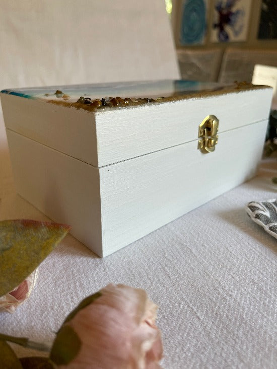 Hand-painted wooden box adorned with resin art depicting ocean waves, seashells, and sand, a unique and artistic product.