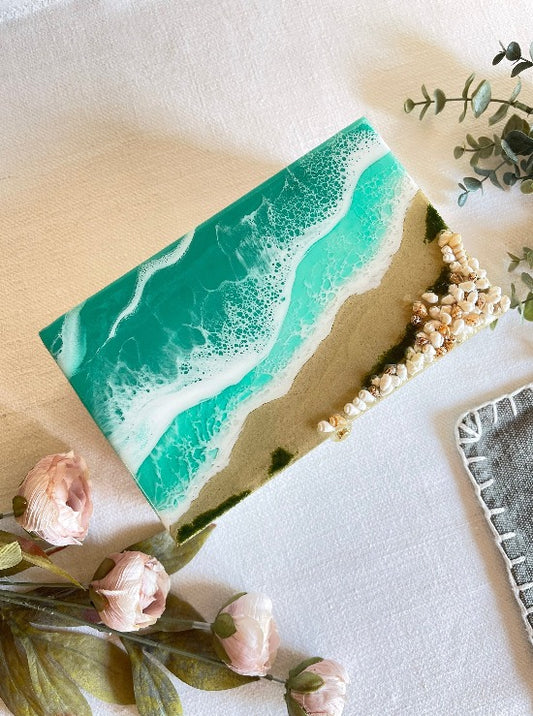 Hand-painted wooden box adorned with resin art depicting ocean waves, seashells, and sand, a unique and artistic product.