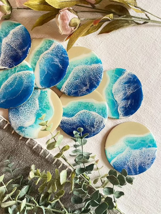 Round resin art coasters featuring a blue color palette with sand and ocean waves design.