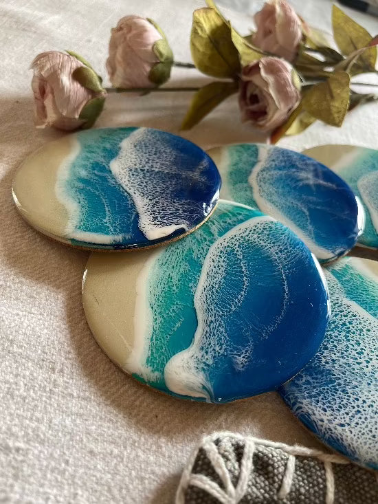 Round resin art coasters featuring a blue color palette with sand and ocean waves design.