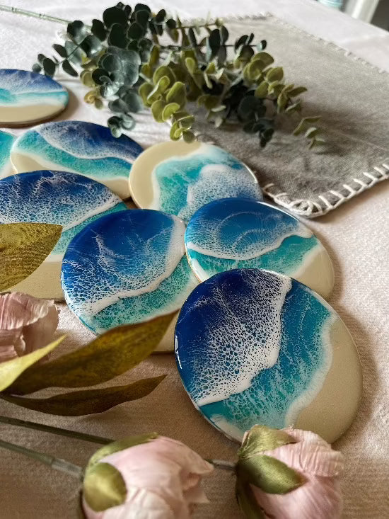 Round resin art coasters featuring a blue color palette with sand and ocean waves design.